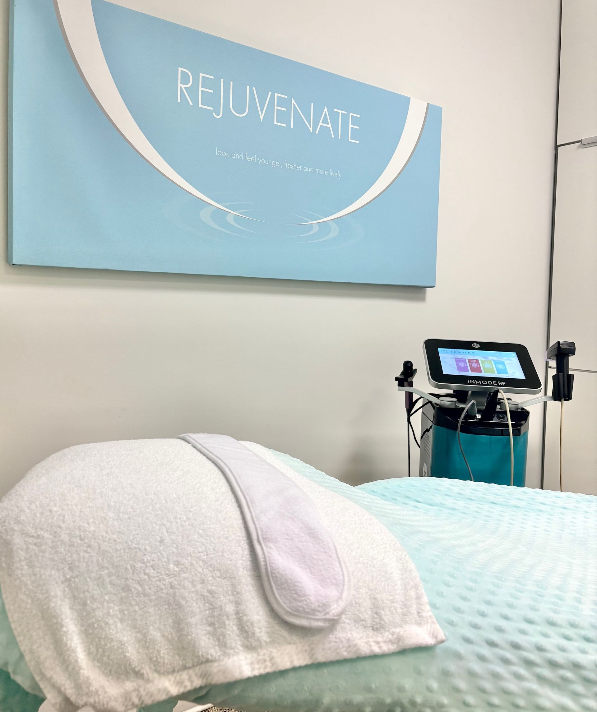 Modern medical treatment room with a blue exam table and wall art.