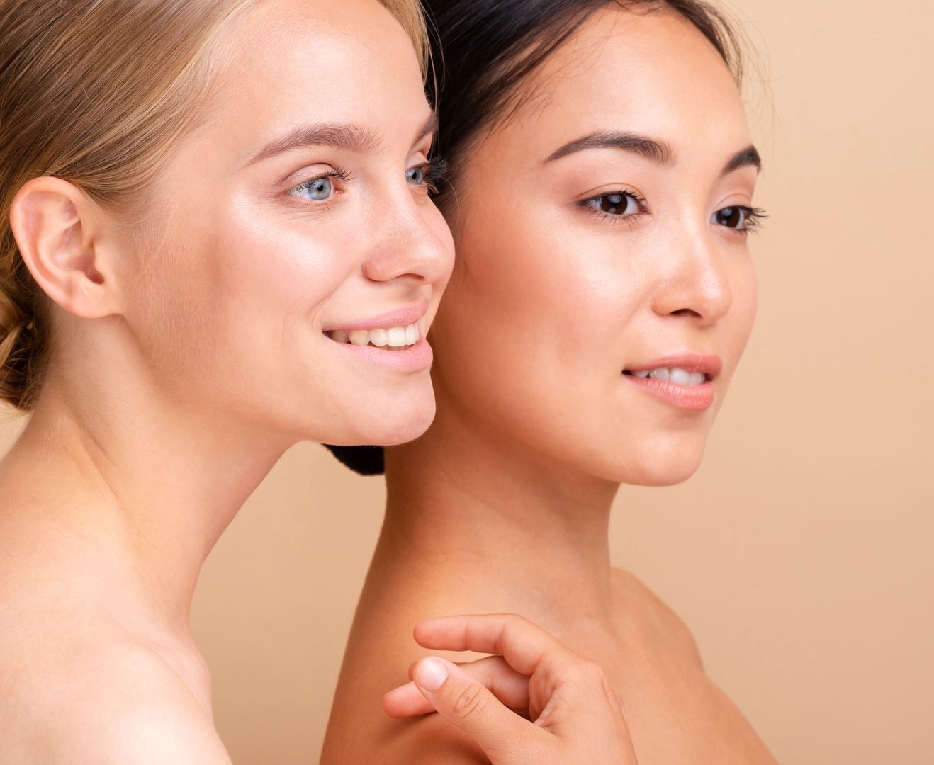 Two beautiful women are standing next to each other and smiling.