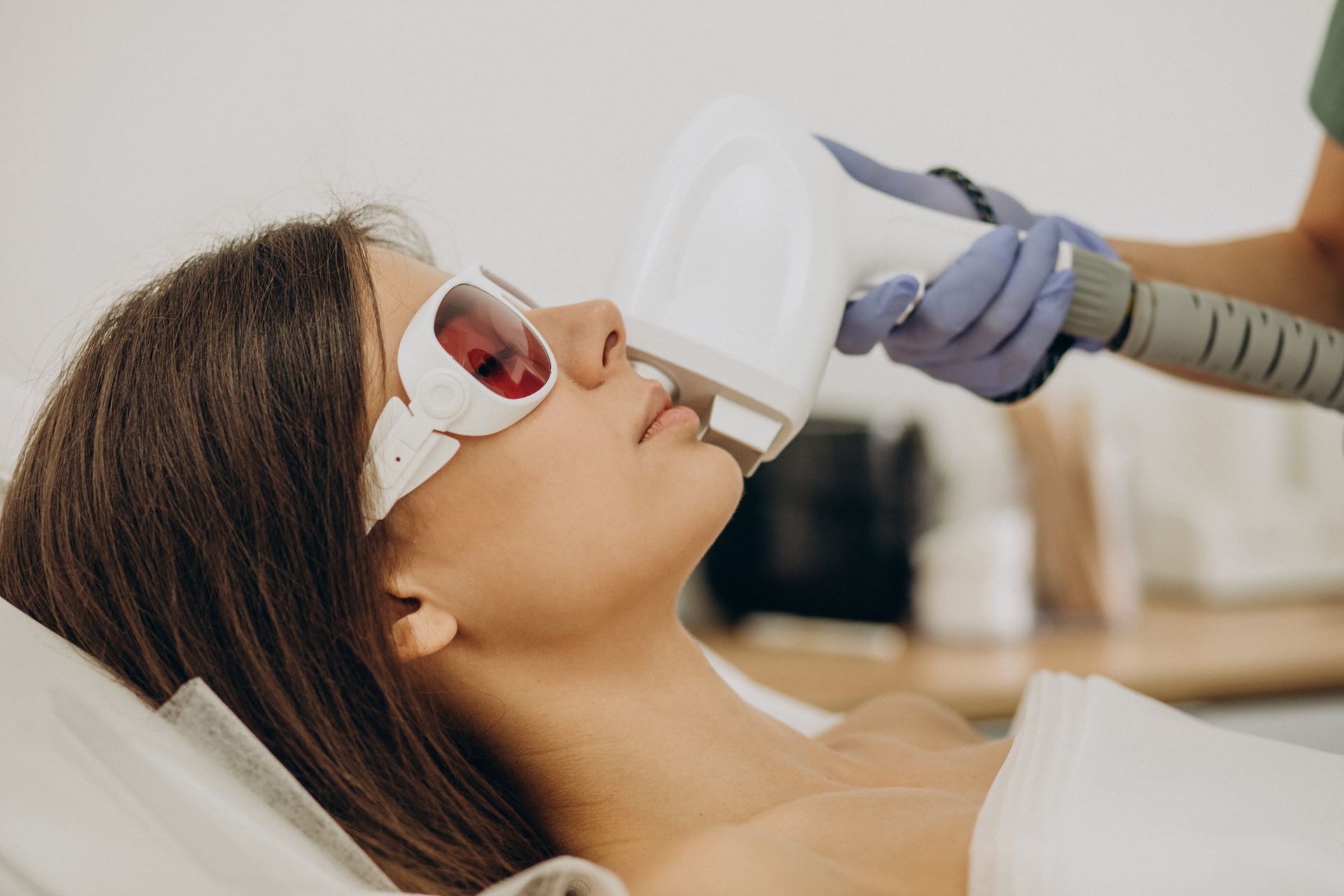 A woman is getting an IPL rejuvenation treatment on her face.