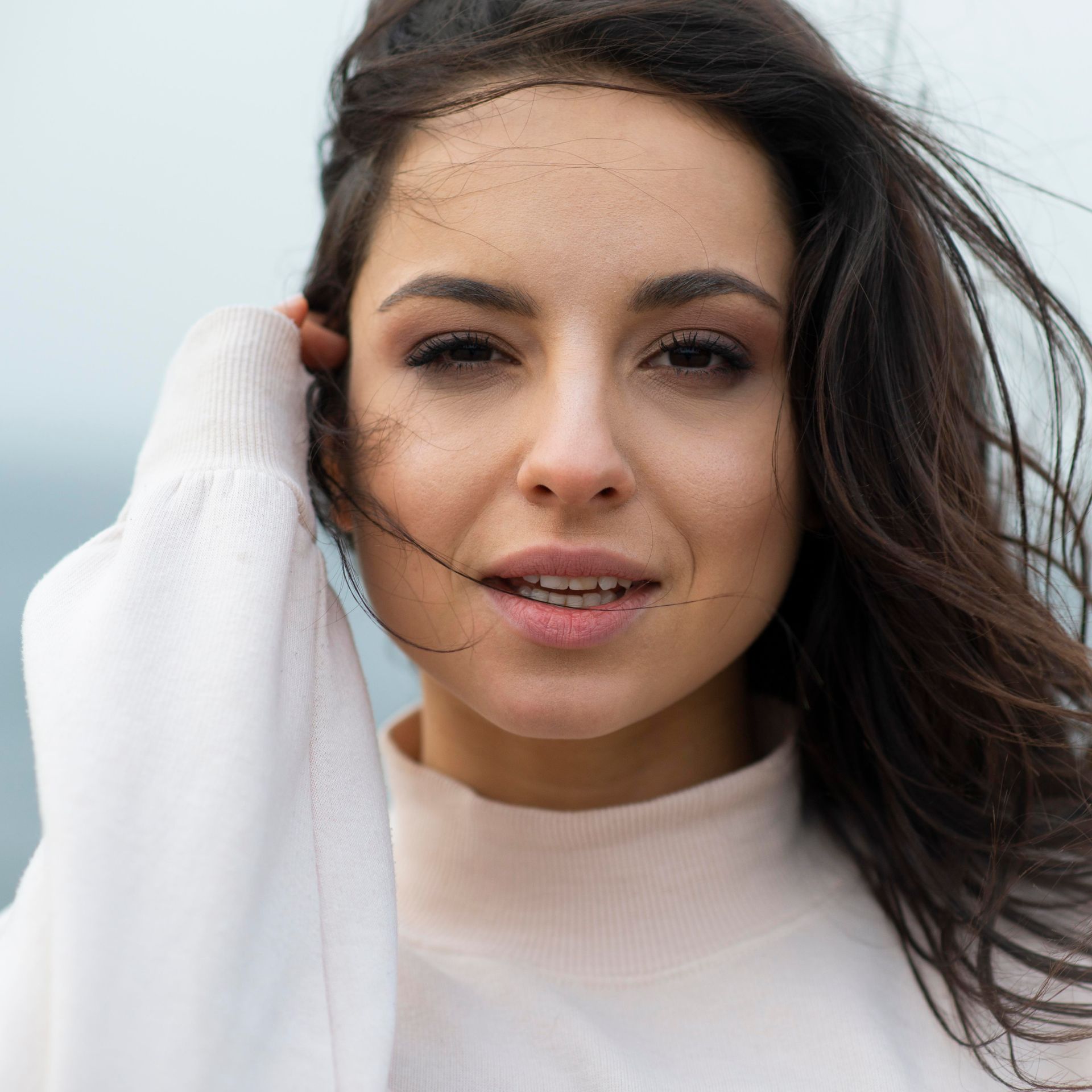 A close up of a woman's face with her hair blowing in the wind.