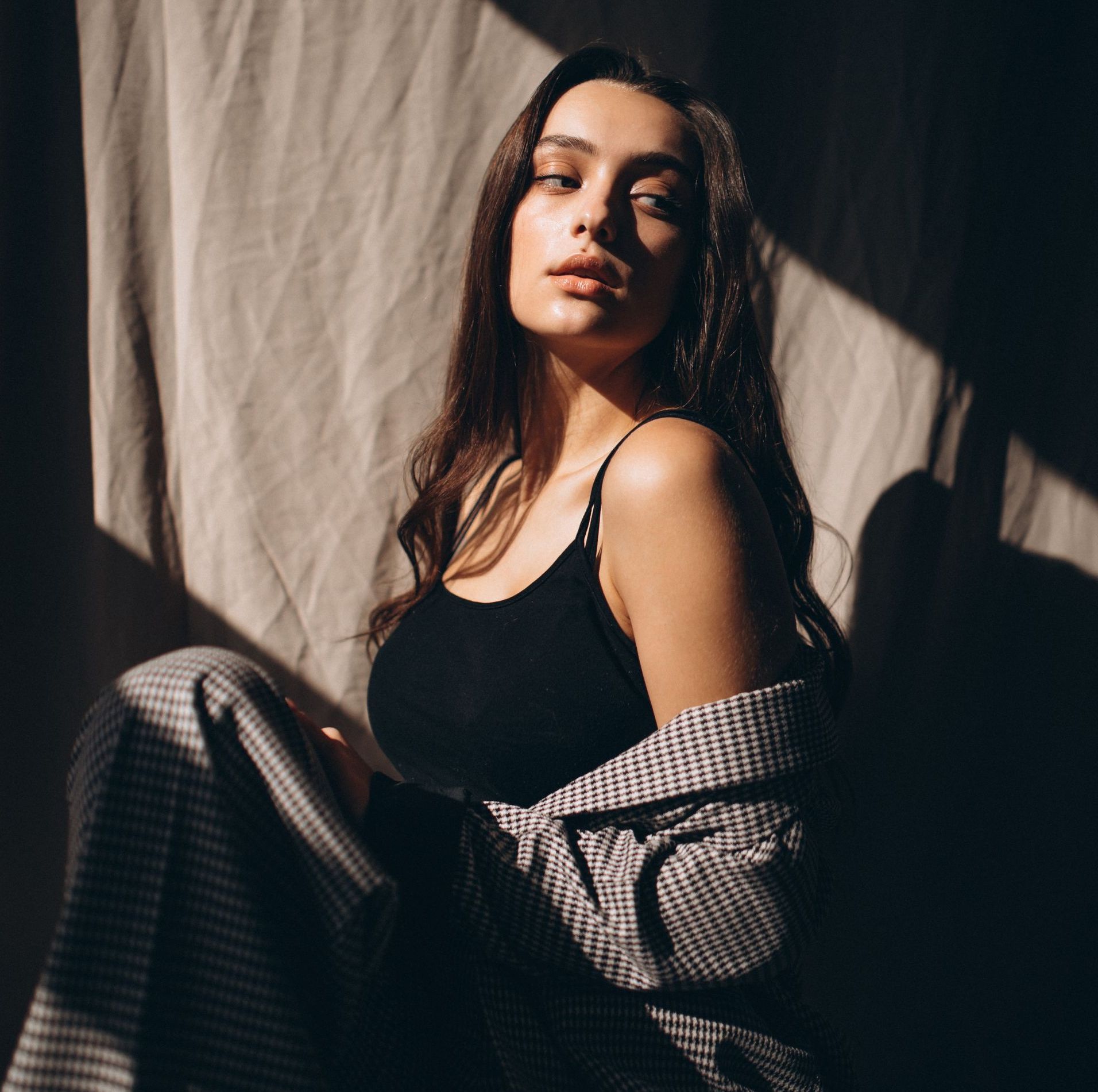 The woman is wearing a black tank top and a plaid jacket.
