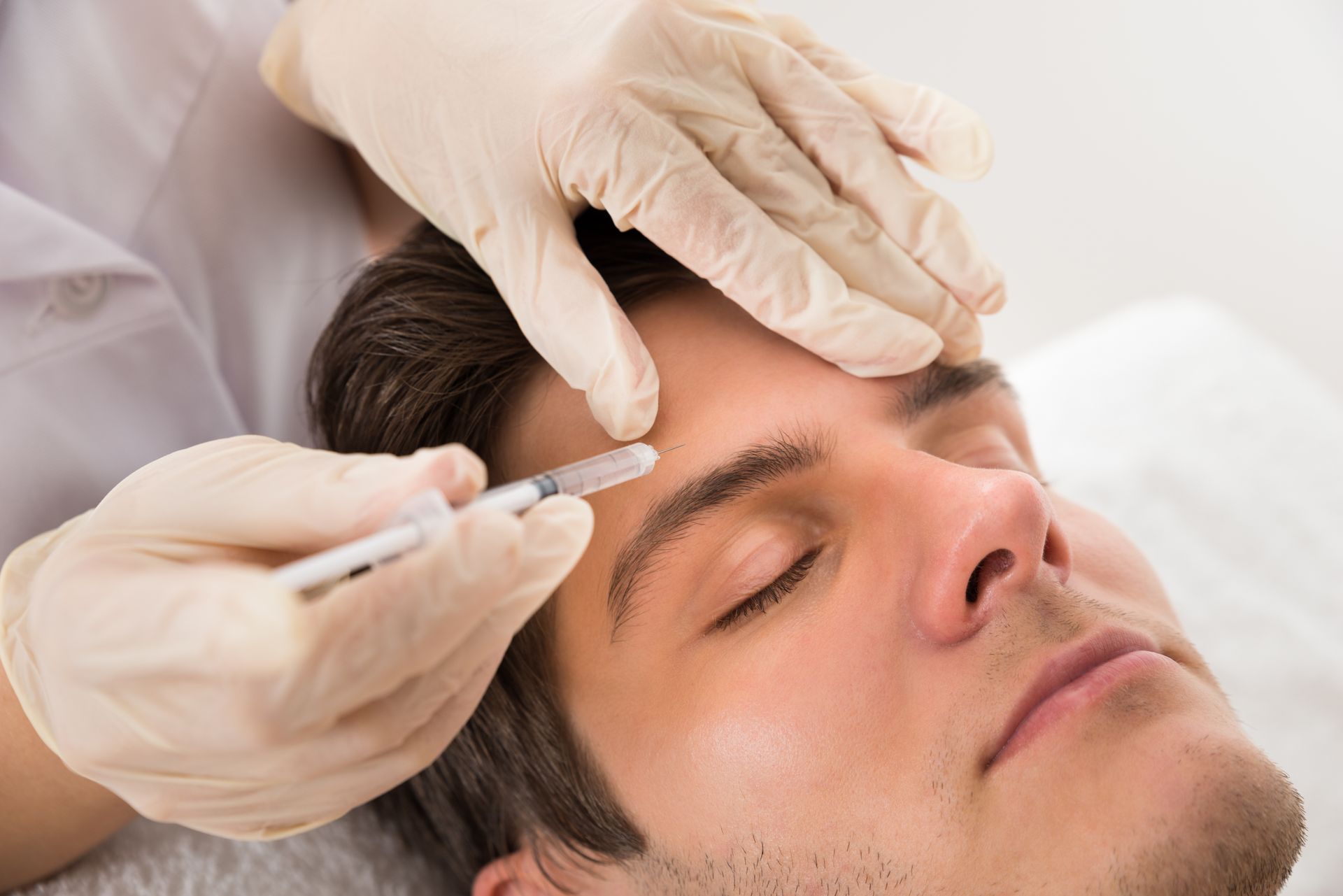 A man is getting a botox injection in her forehead.