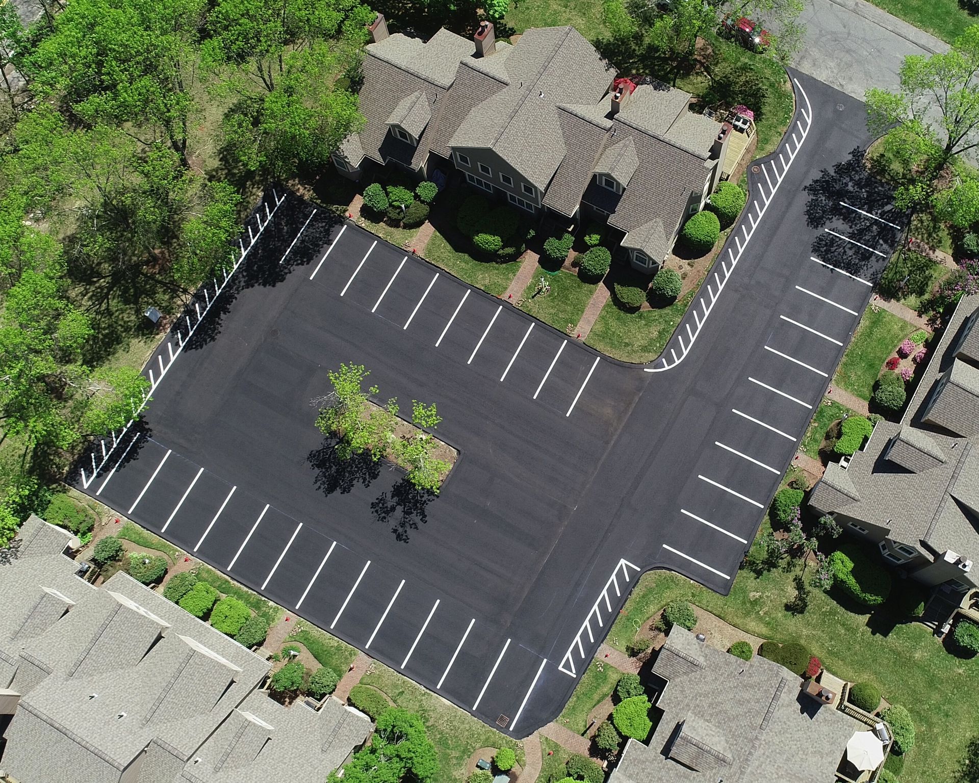 Aerial view of a parking lot next to a building with parking space markings.