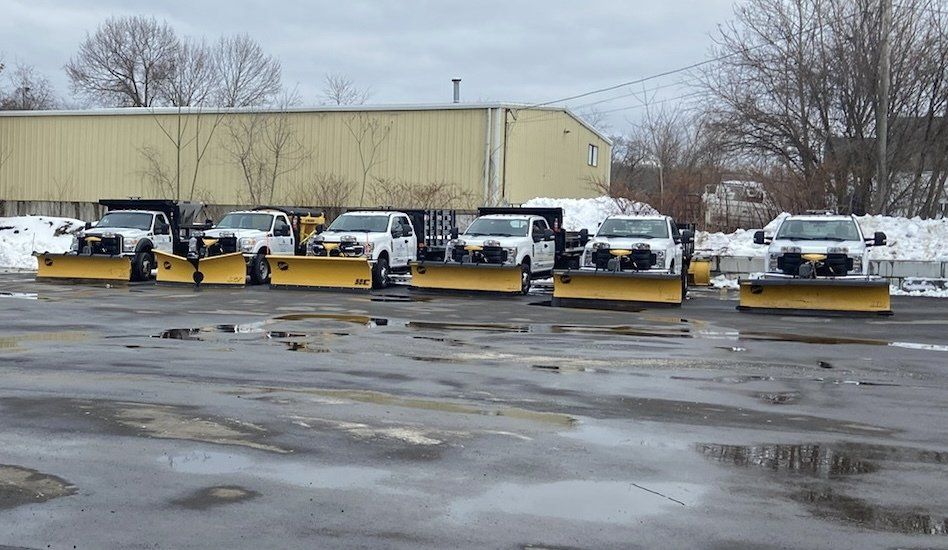 Snowplows lined up in a parking lot, ready for winter weather.