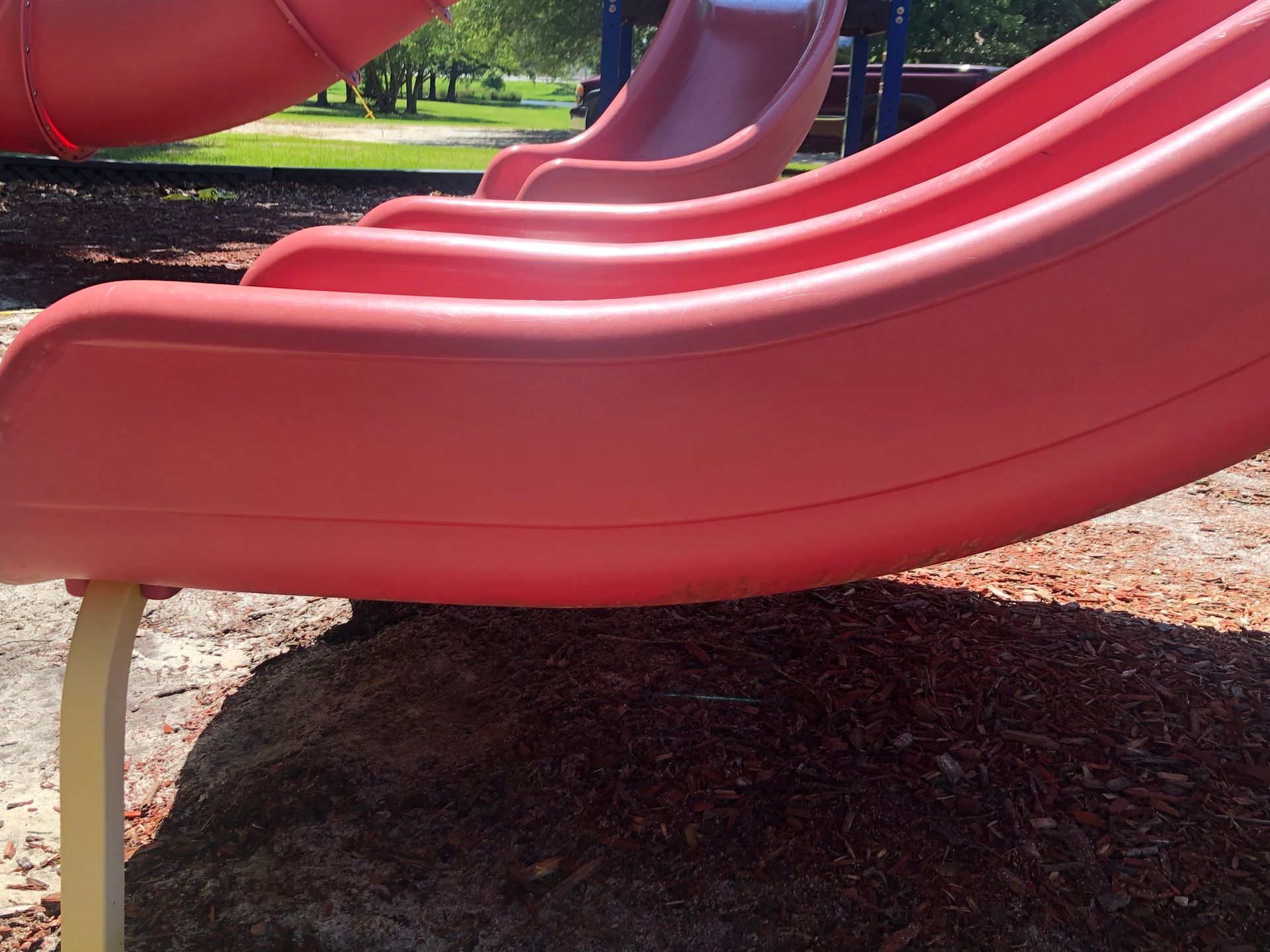 A row of pink slides are lined up in a park