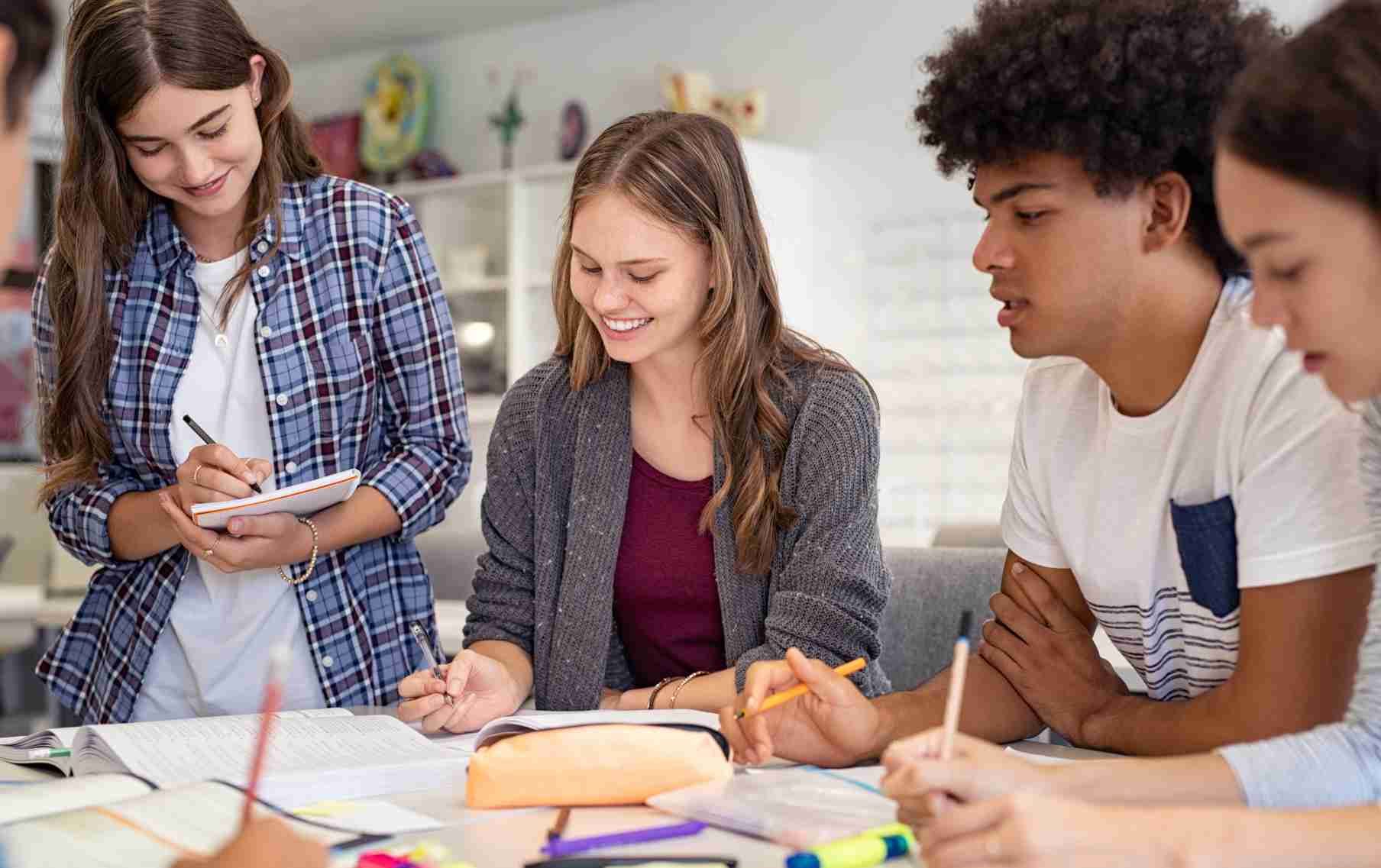 A group of students leaders sitting around a table doing a project.