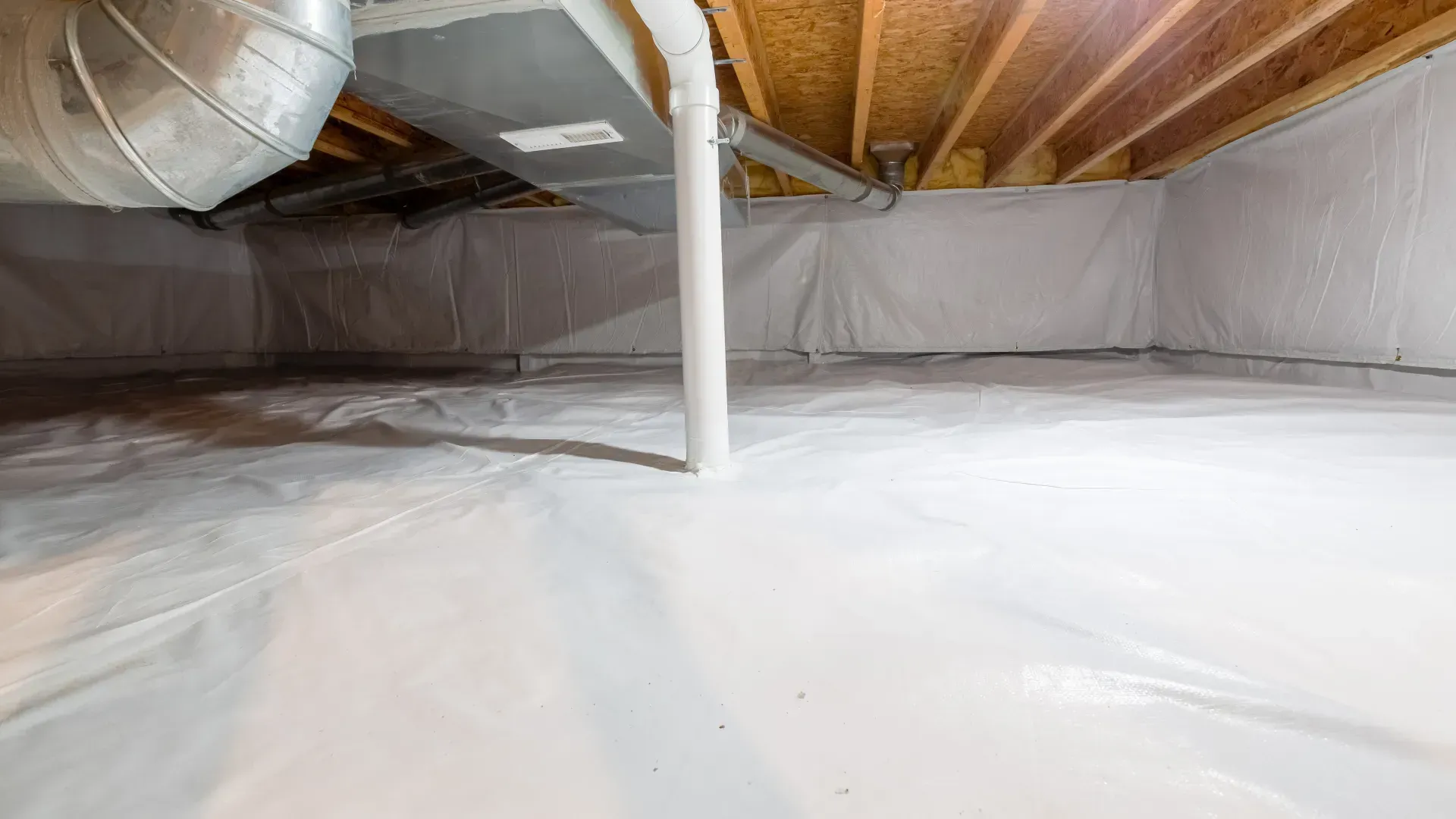Basement with white vapor barrier on floor and walls; support column in the center.