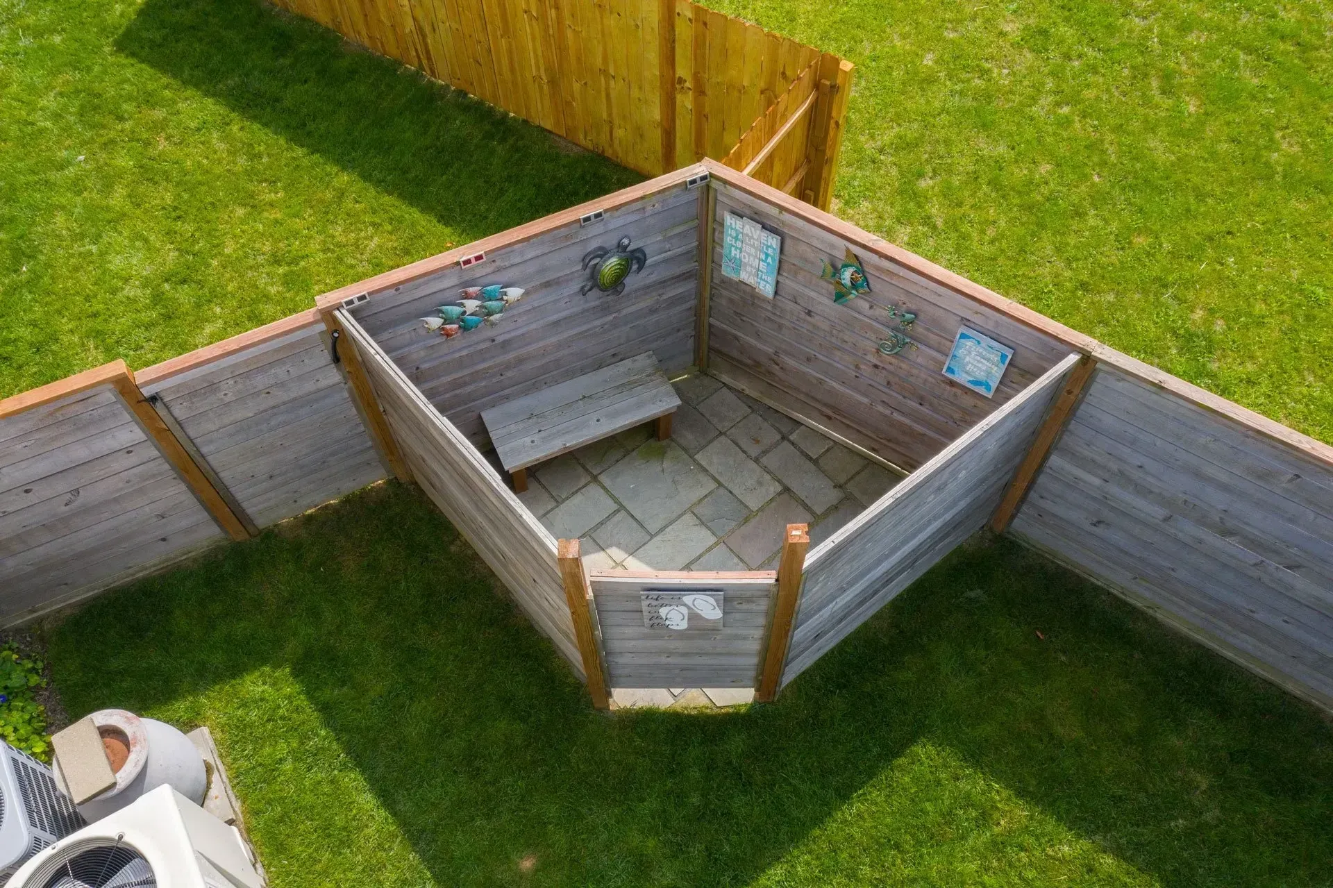 An aerial view of a backyard with a wooden fence and a bench.