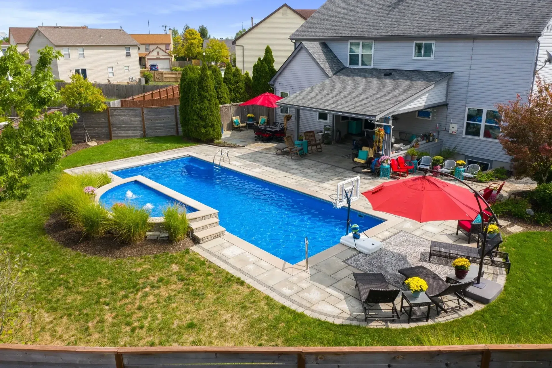 An aerial view of a large swimming pool in the backyard of a house.