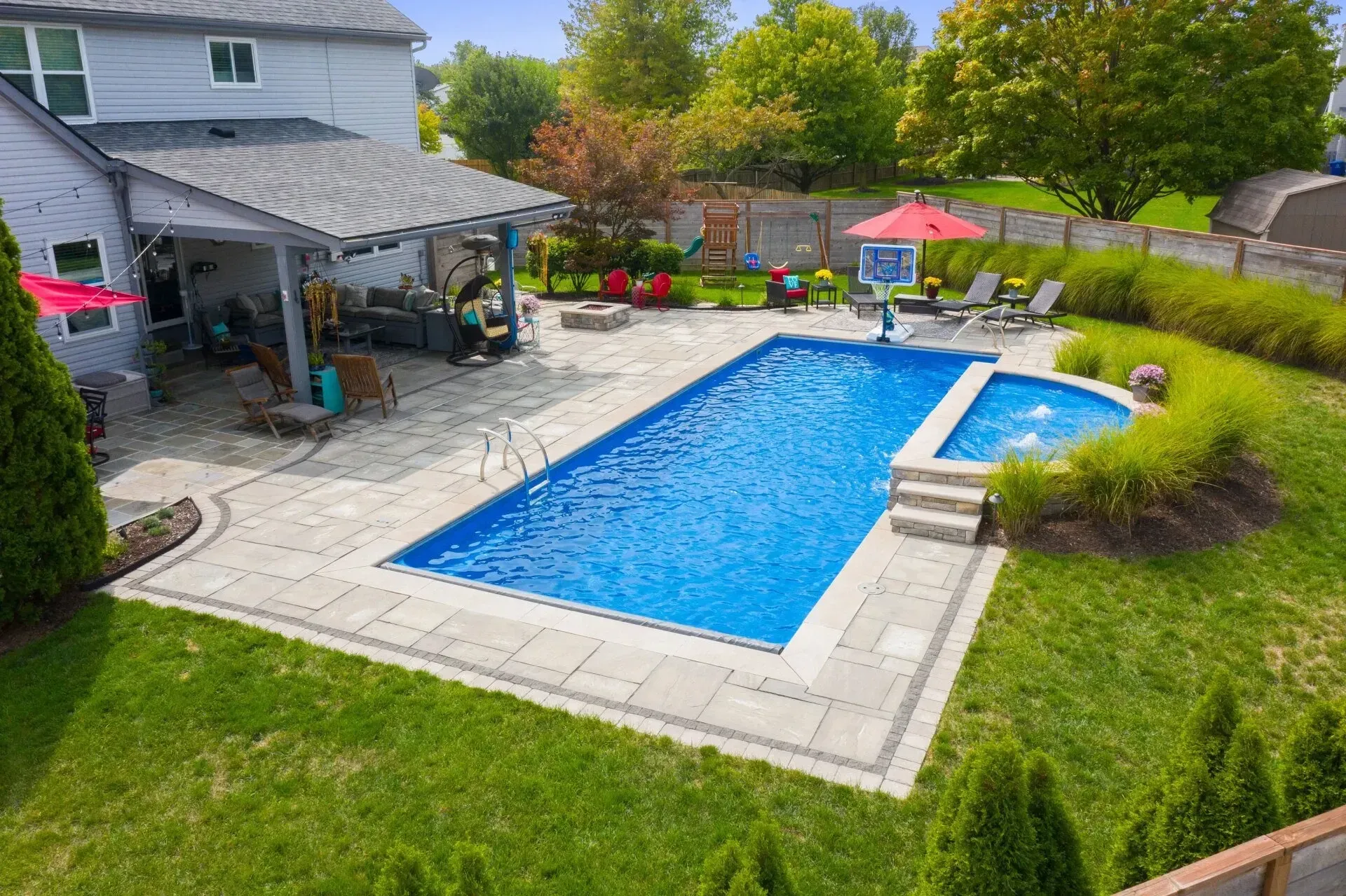 An aerial view of a large swimming pool in the backyard of a house.