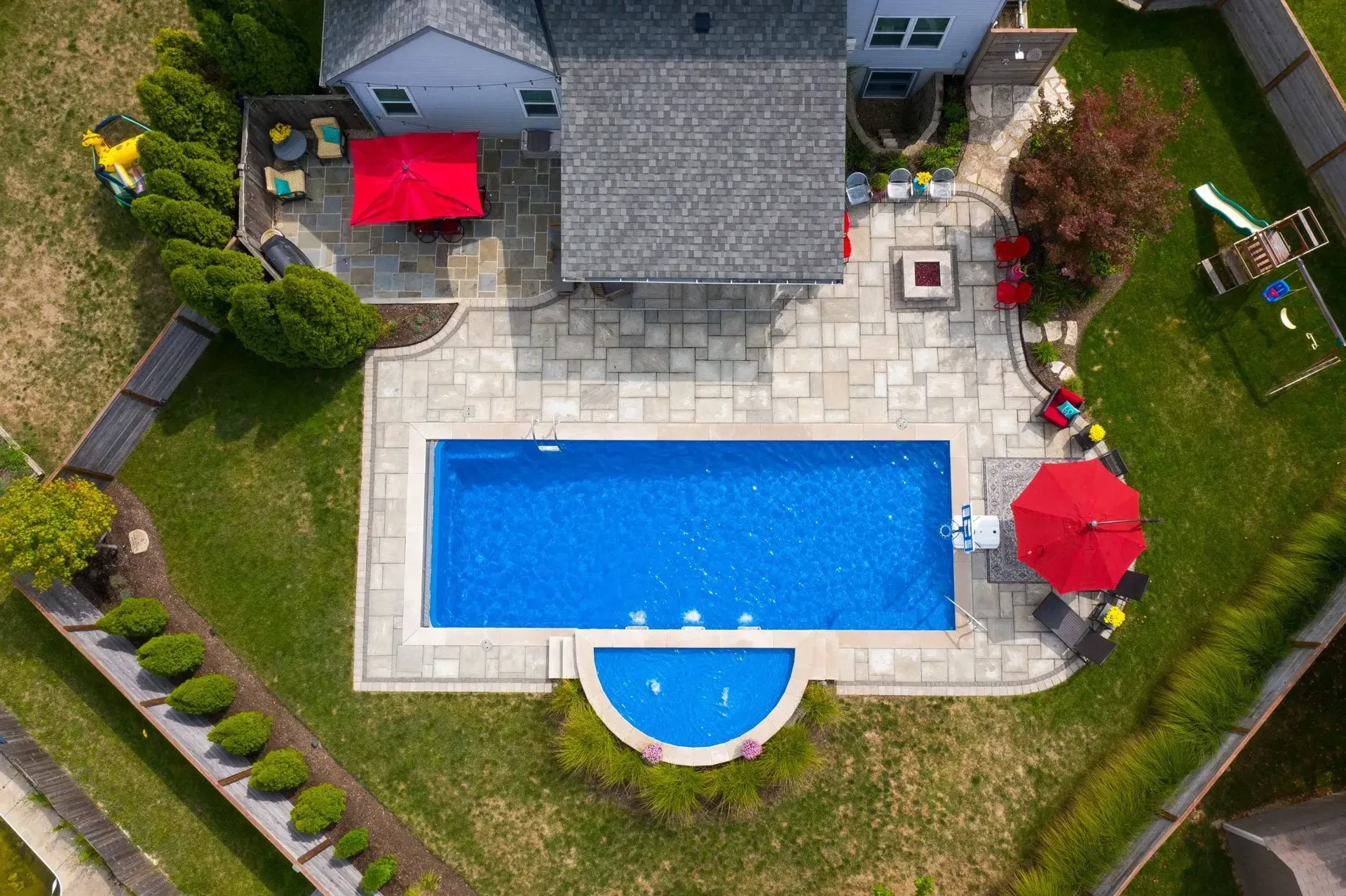 An aerial view of a large swimming pool in the backyard of a house.