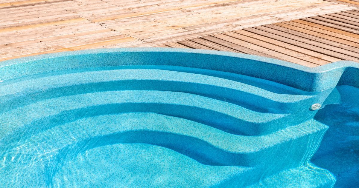 A fiberglass pool with a wooden deck