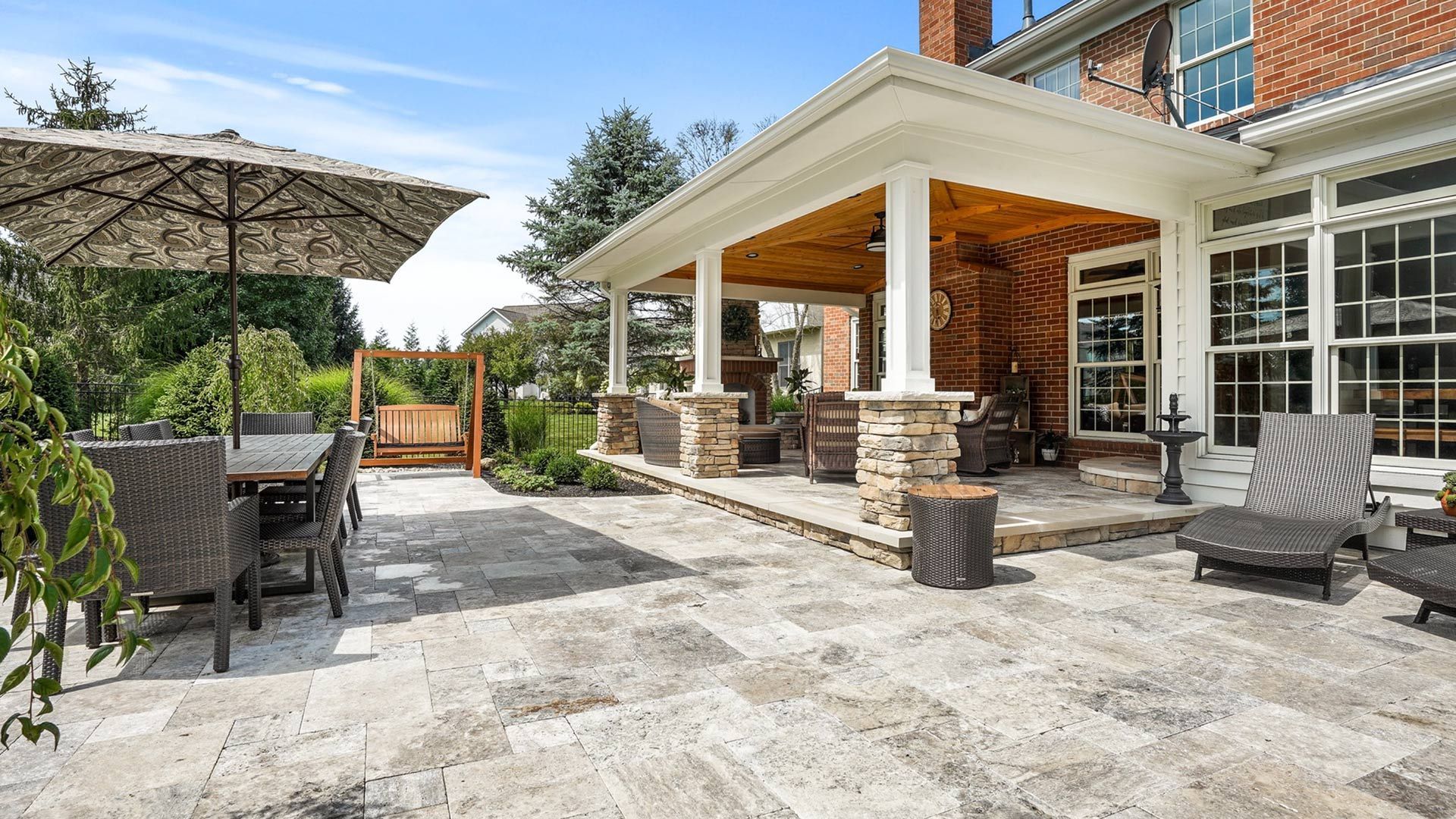 A large patio with umbrellas and chairs in front of a brick house.