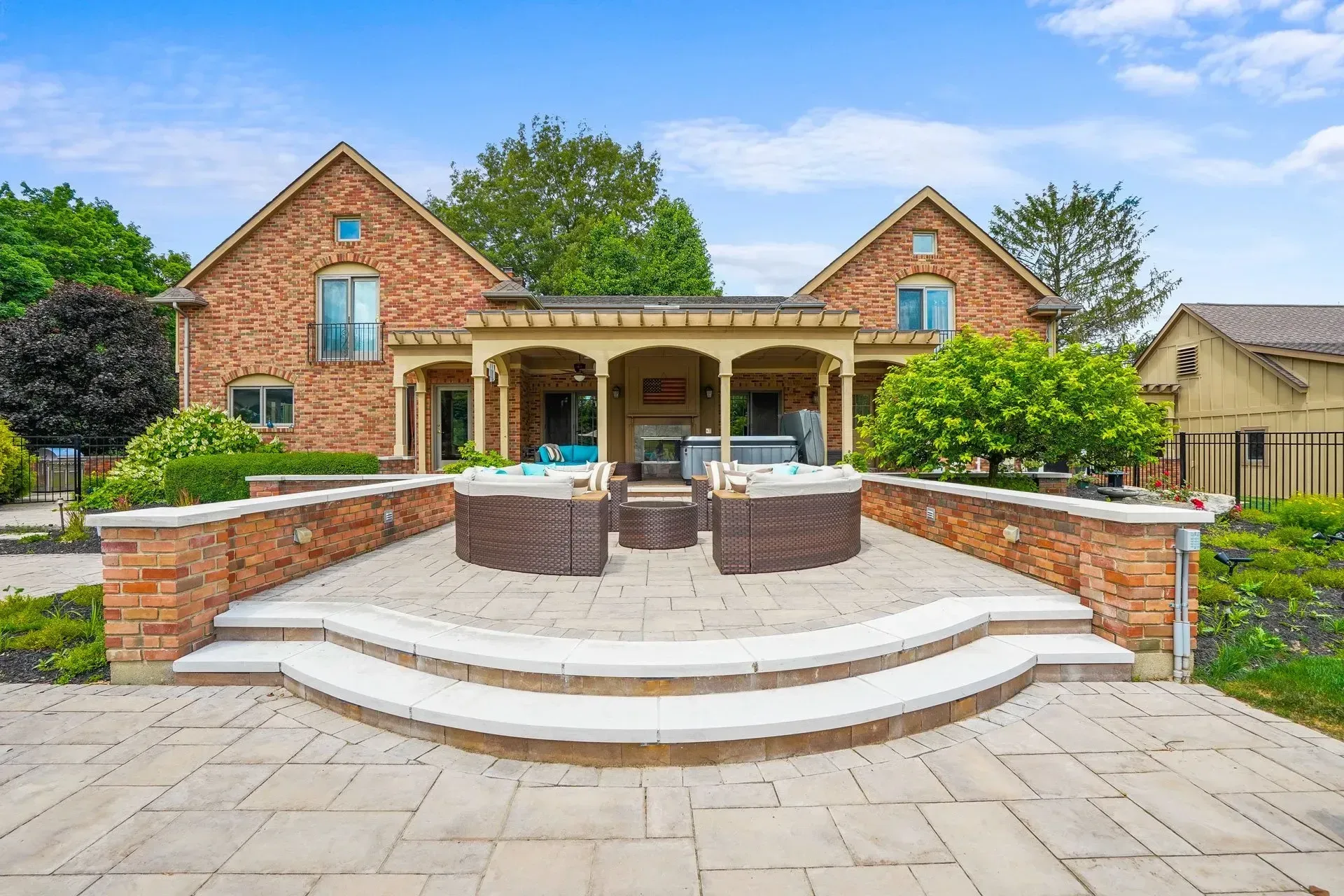 Brick house with a patio featuring seating, and a hot tub under a covered area.