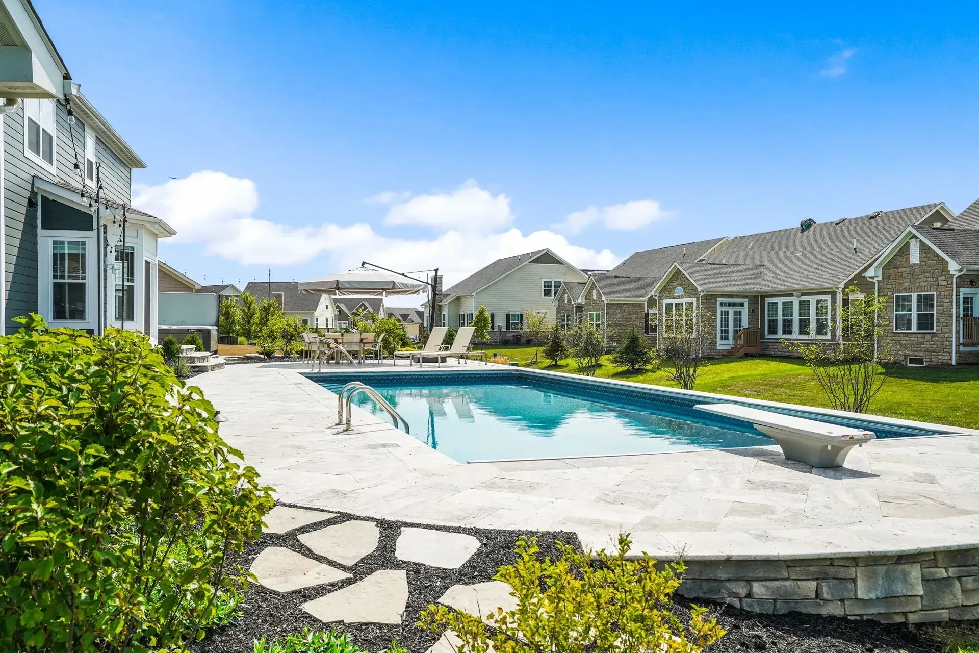 There is a large swimming pool in the backyard of a house.