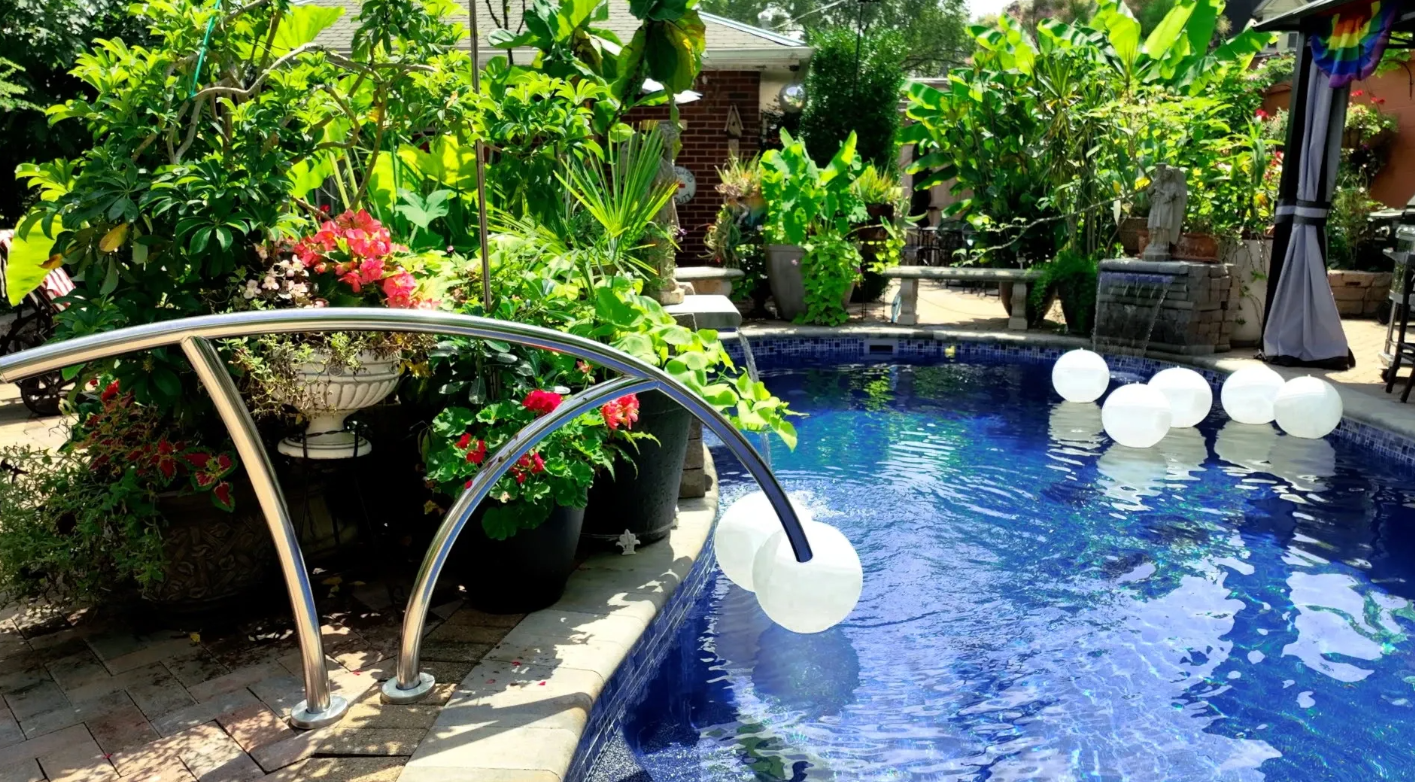 A pool surrounded a garden with a waterfall and white garden balls