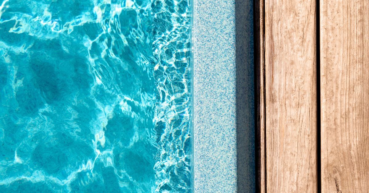 A pool side with a wooden deck
