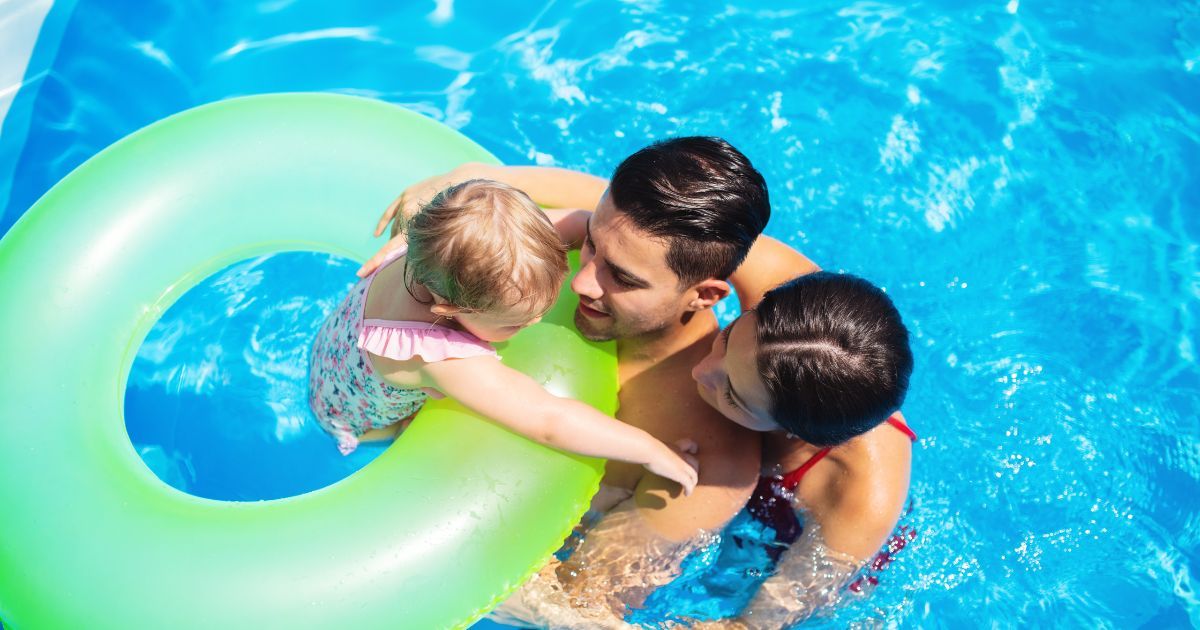 A couple holding their baby in a pool.