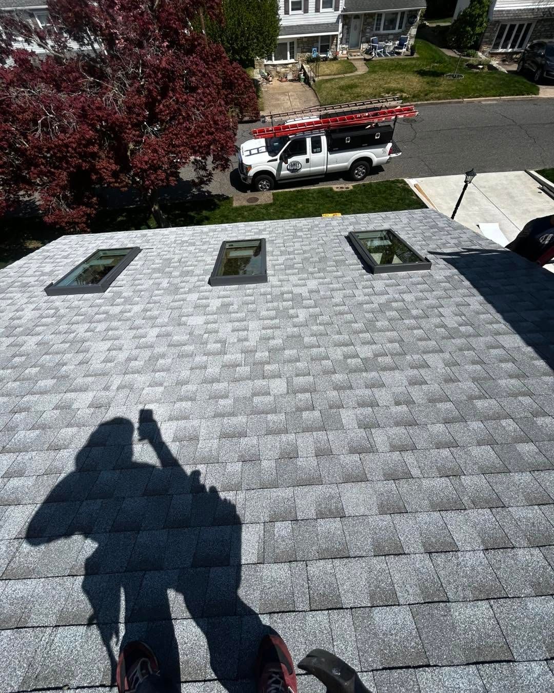 Rooftop view with three skylights, a worker shadow, and a utility truck on the street below