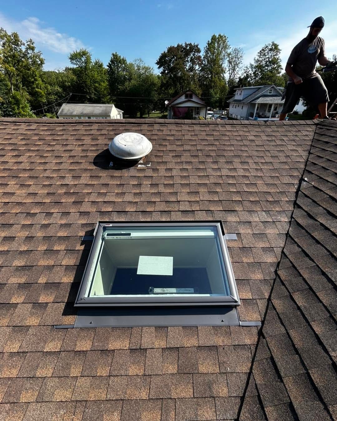 Roof with skylight and vent; person standing on the right side near the roof ridge.