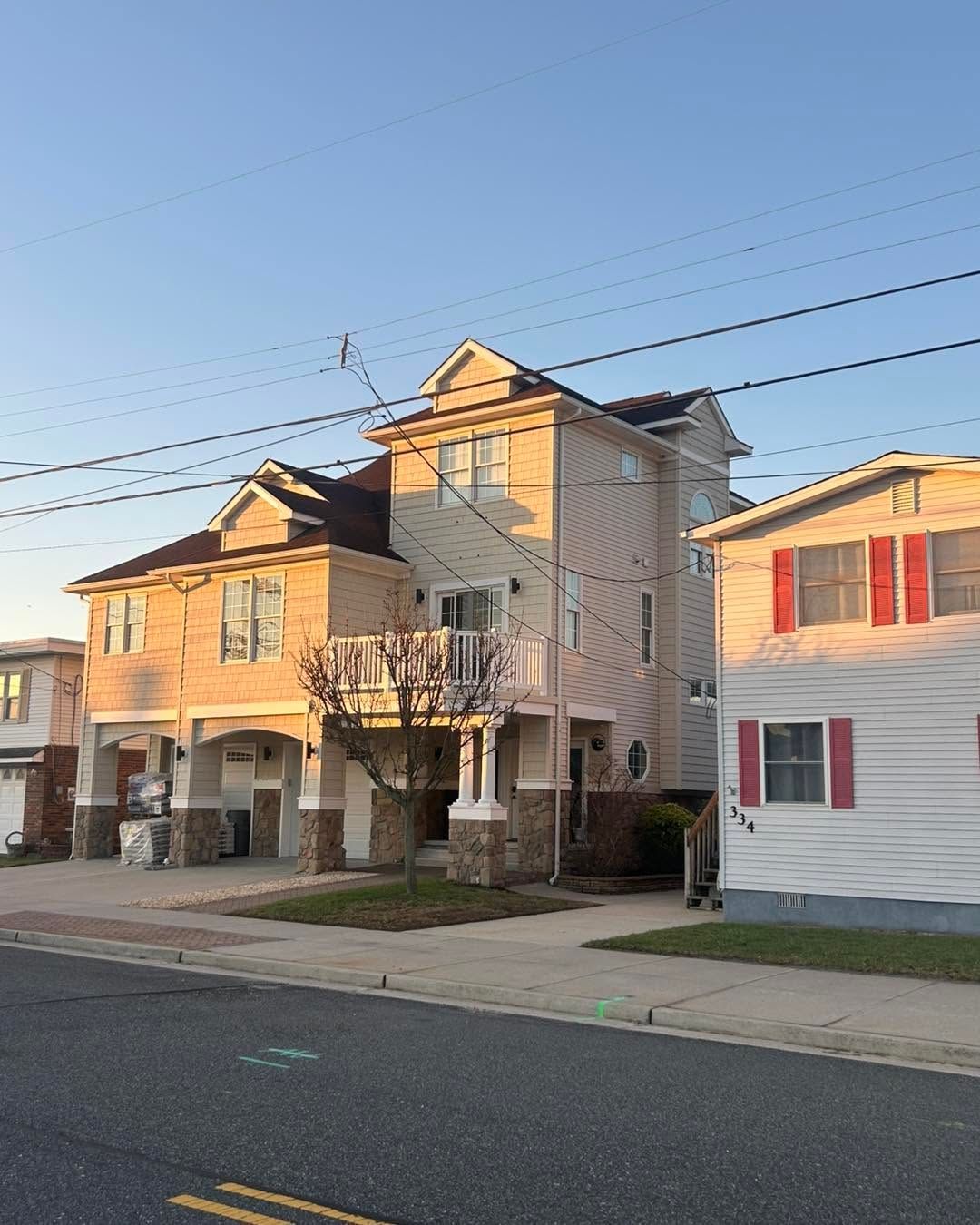 Row of multi-story houses on a quiet street at sunset, with overhead power lines and parked cars.