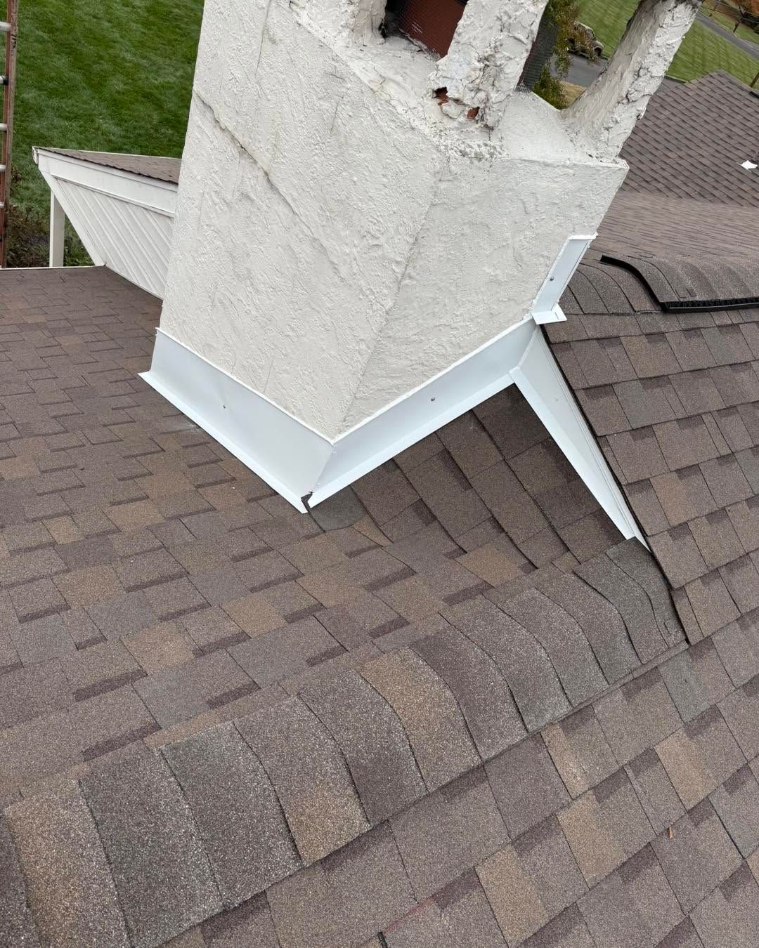 White chimney flashing on a shingled roof with a small slanted metal roof detail.
