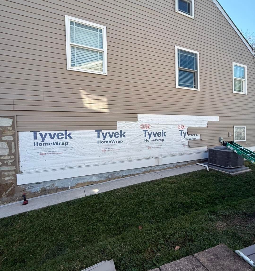 House exterior with Tyvek house wrap installed along the lower wall under three windows.