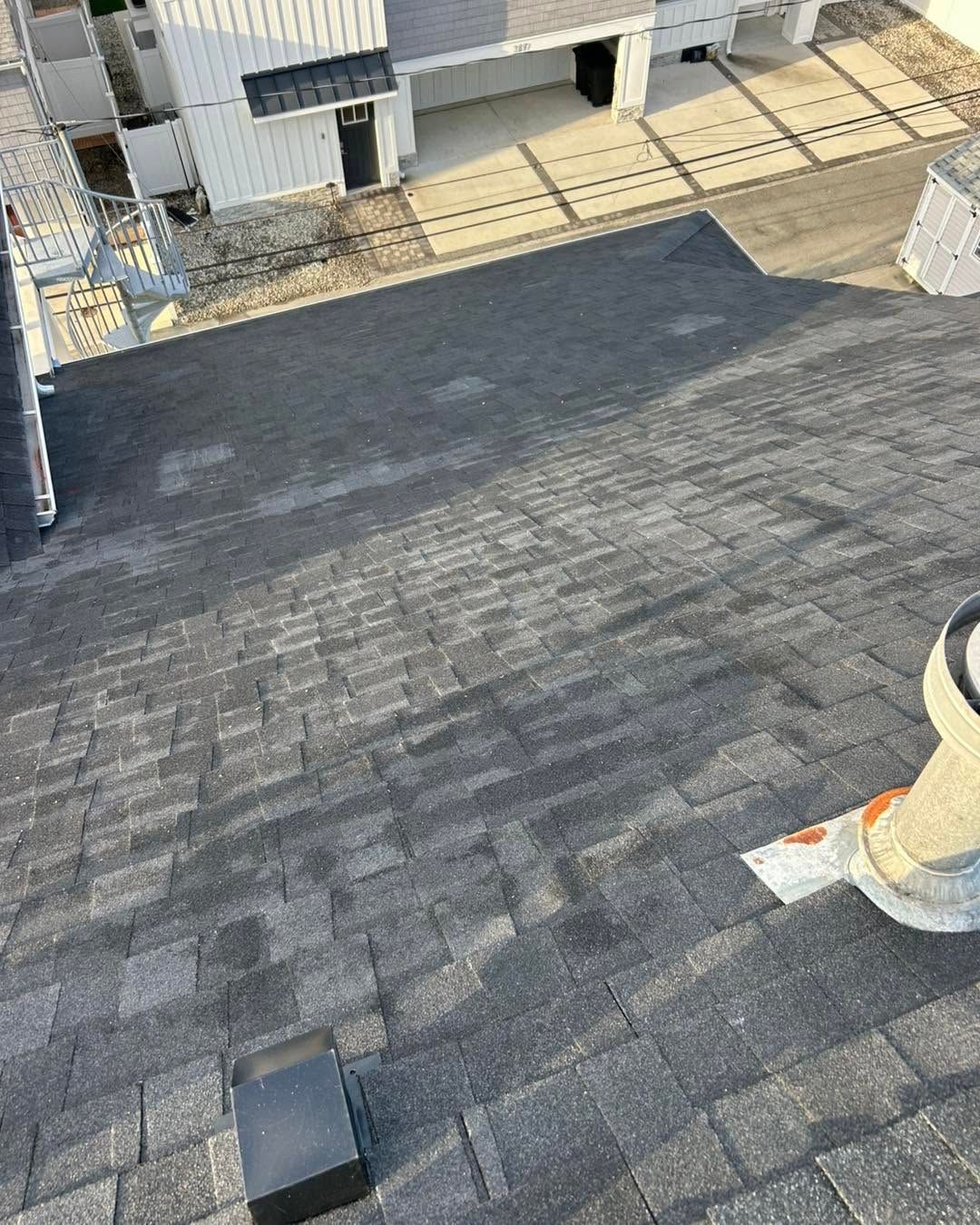 Flat dark shingle roof with a small vent and a person’s boot visible at the lower right edge.