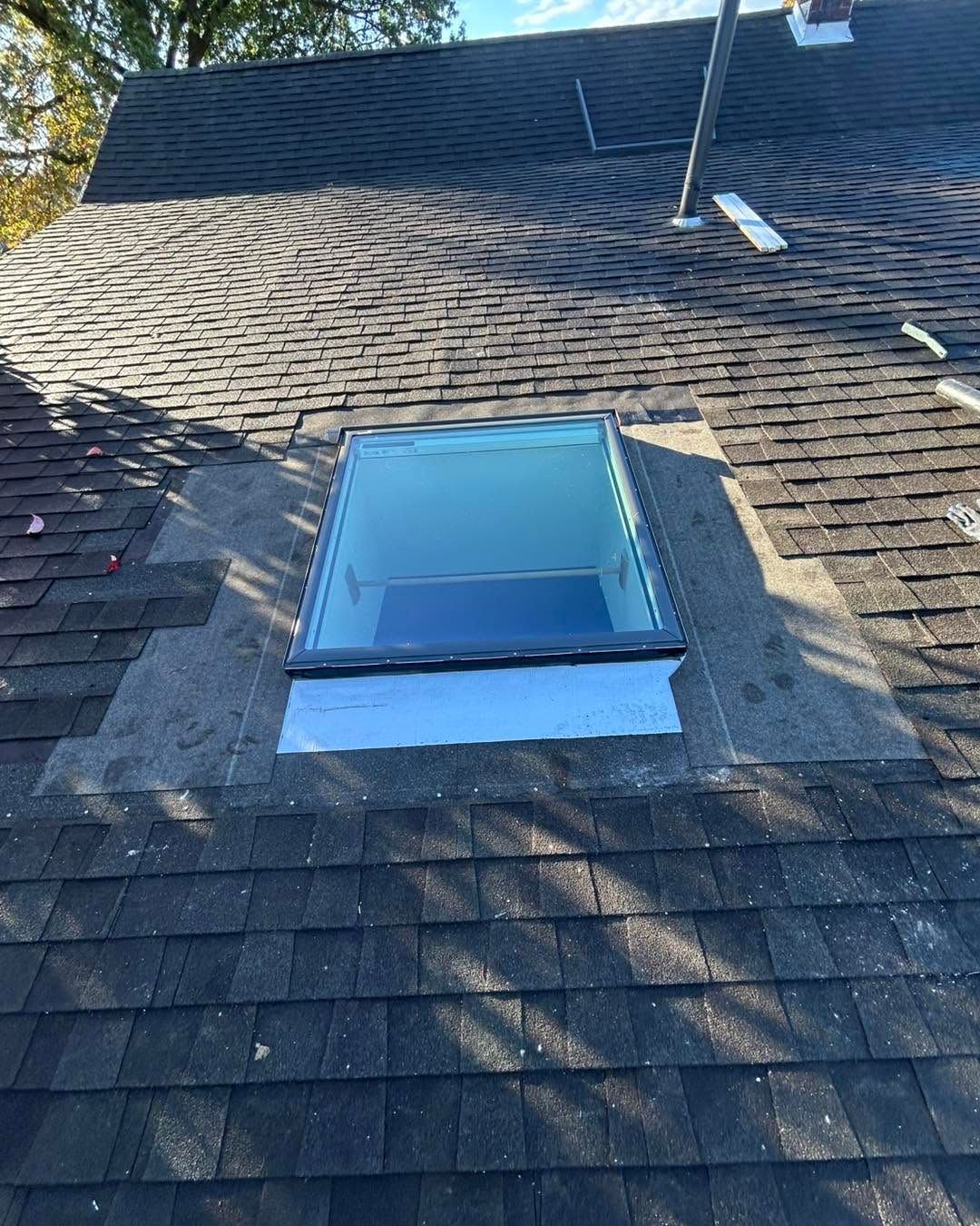 Rooftop skylight with blue glass on a shingled roof in sunlight
