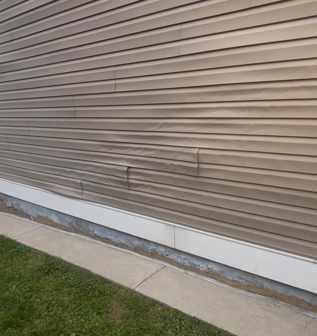 Beige vinyl siding wall above a concrete walkway and small strip of grass