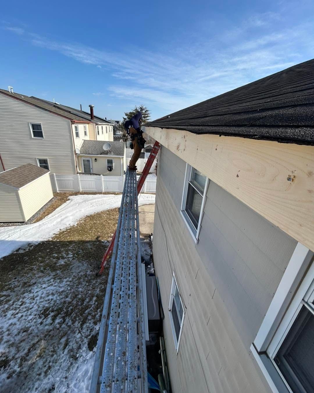 Long metal ladder spanning between two houses along a narrow gap under a blue sky