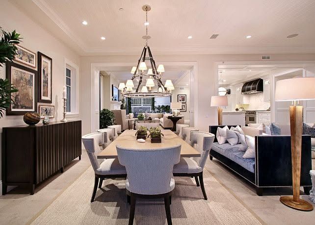 Elegant beige dining room with chandelier, long table, upholstered chairs, and mirrored decor