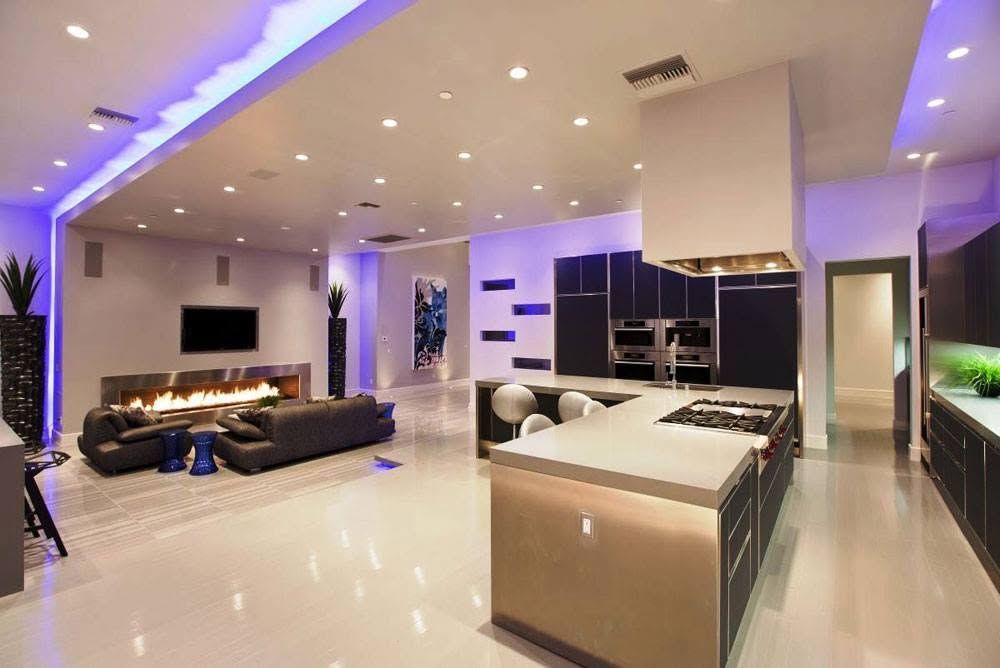Modern open-plan living room with glossy floors, black sofas, fireplace, and kitchen island under purple lighting