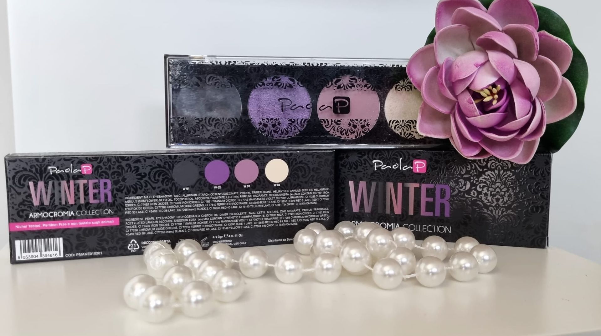 Palette di ombretti nella confezione della collezione invernale, con perle e un fiore su uno scaffale.