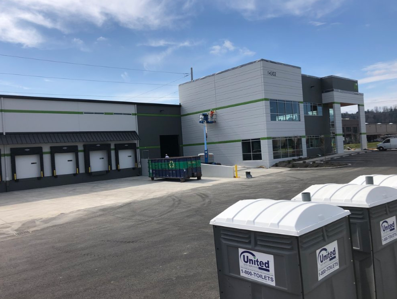 Two portable toilets are in front of a building under construction.