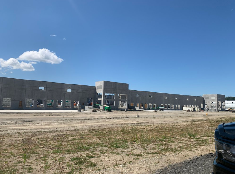 A car is parked in front of a large building under construction.