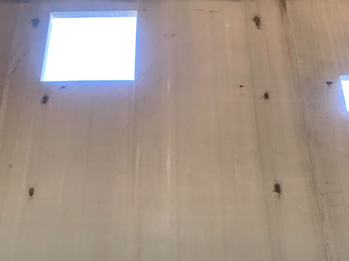 A white wall with two square windows in it.