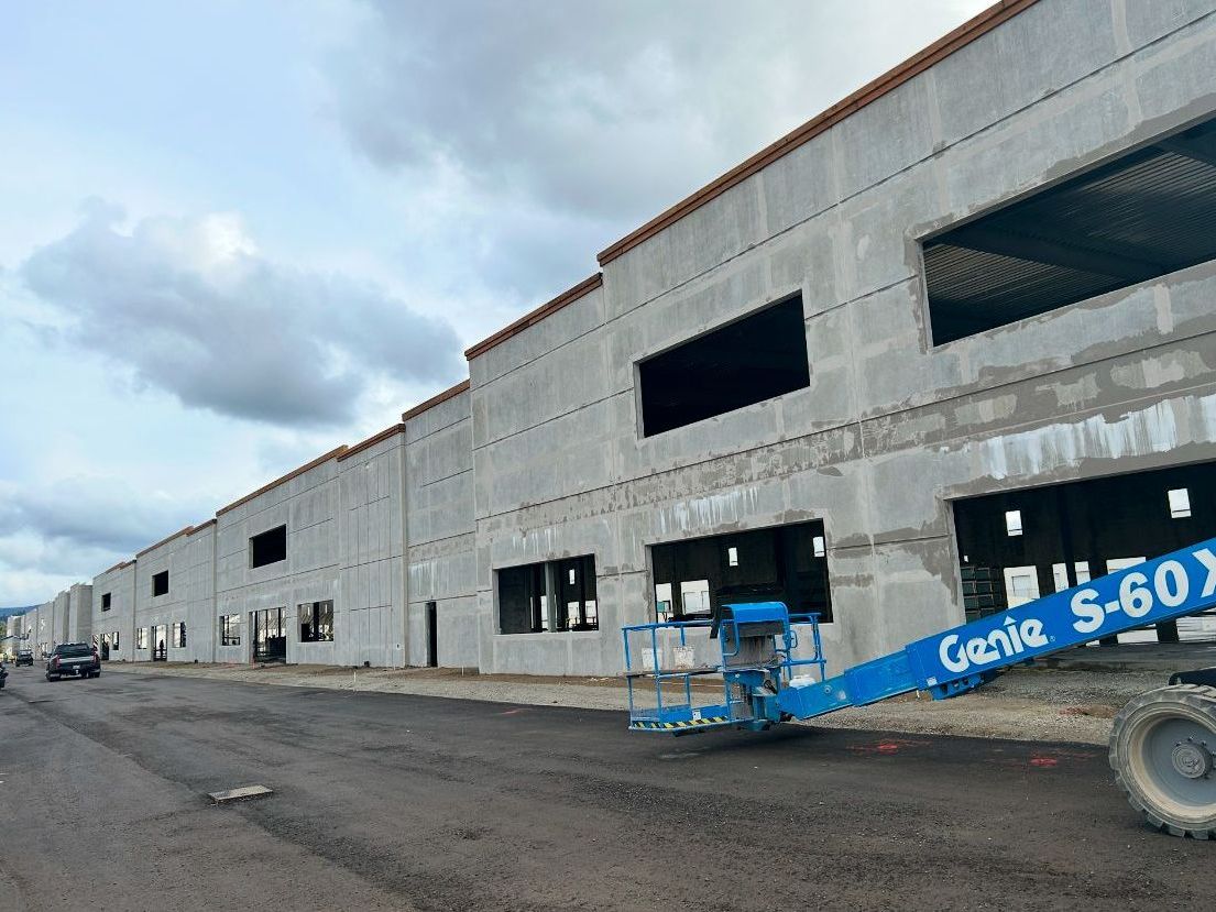 A blue genie lift is parked in front of a building under construction.