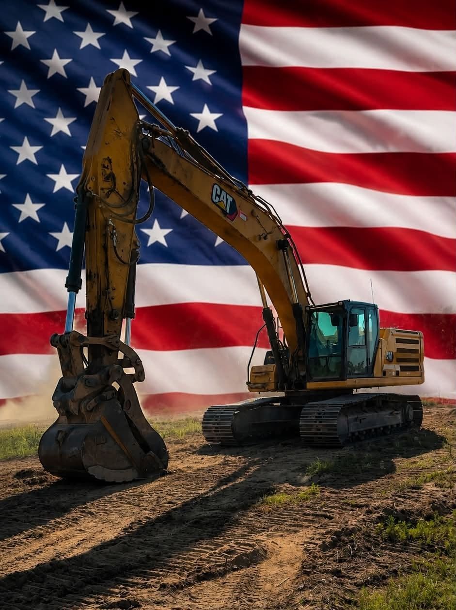 Yellow excavator on dirt in front of a large American flag background
