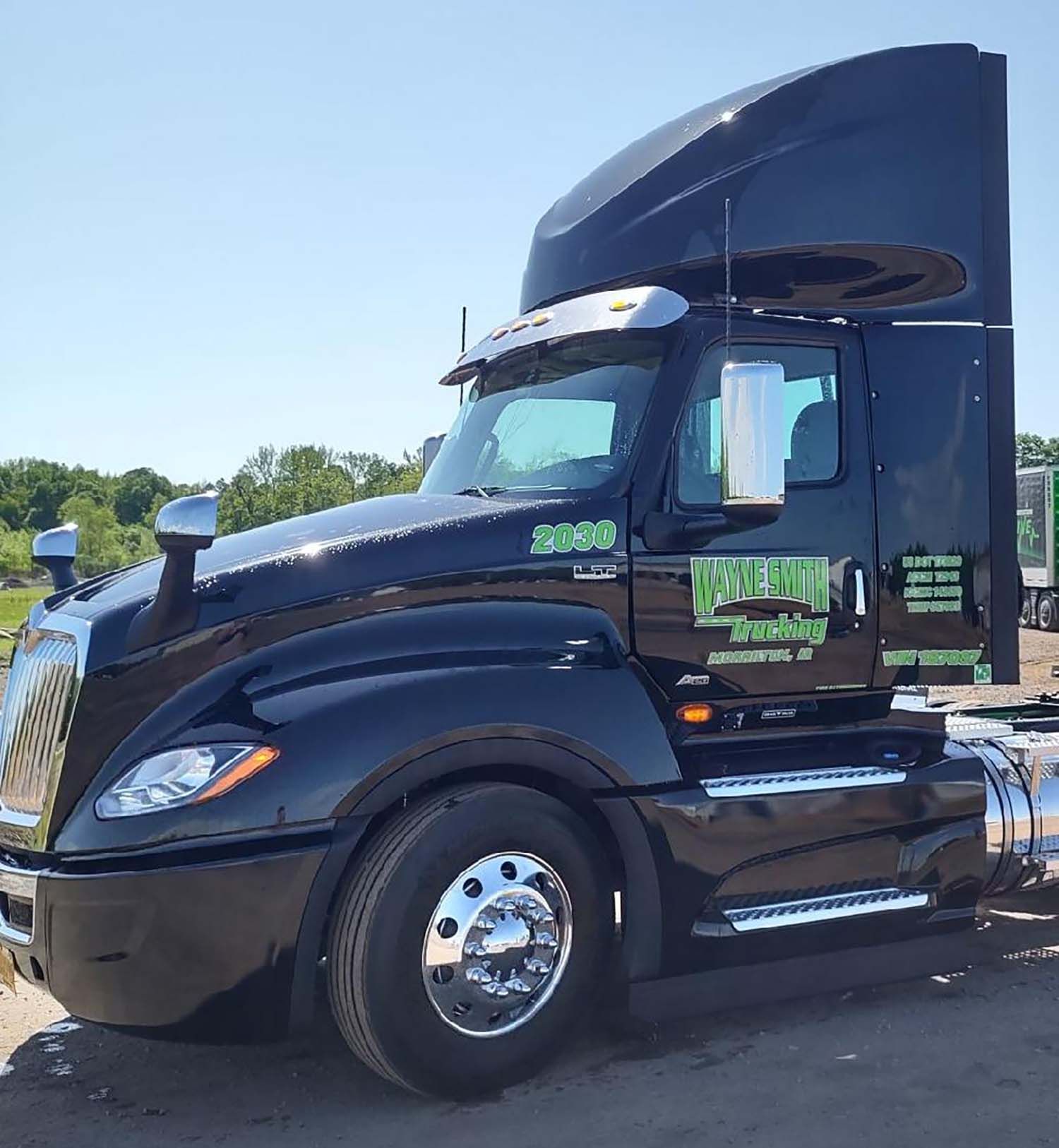 Black semi-truck cab parked outdoors on a sunny day.