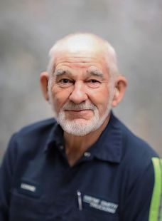 Smiling man in a navy work shirt against a soft gray background