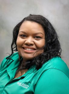 Smiling woman in a green shirt against a gray background