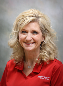 Portrait of a smiling woman in a red shirt against a gray studio background