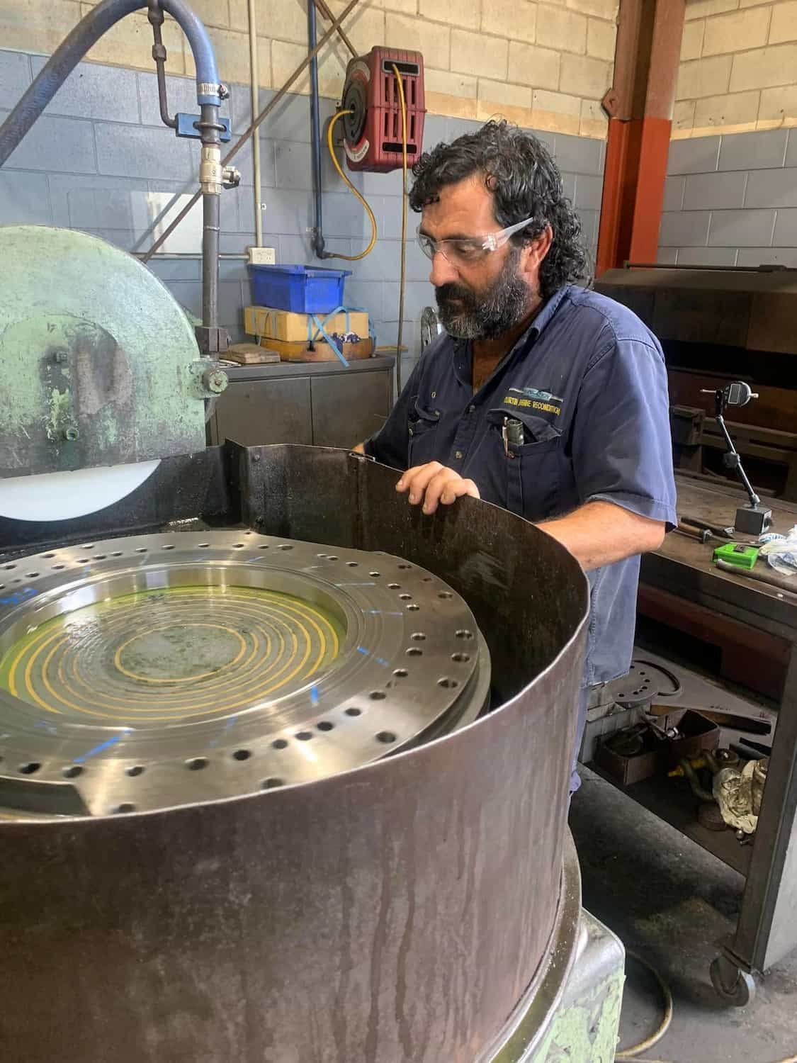 A man is looking at a metal thing— Curtin Engine Reconditioning Pty Ltd In Paget, QLD