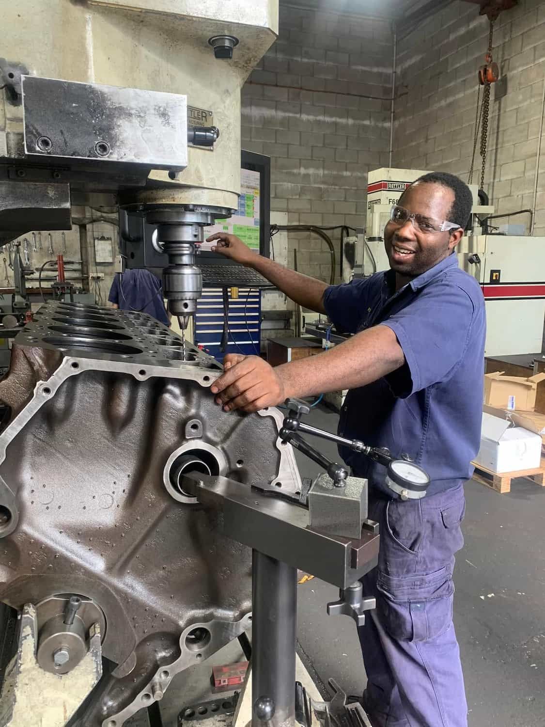 A Man is Working on a Machine in a Factory — Curtin Engine Reconditioning Pty Ltd In Paget, QLD