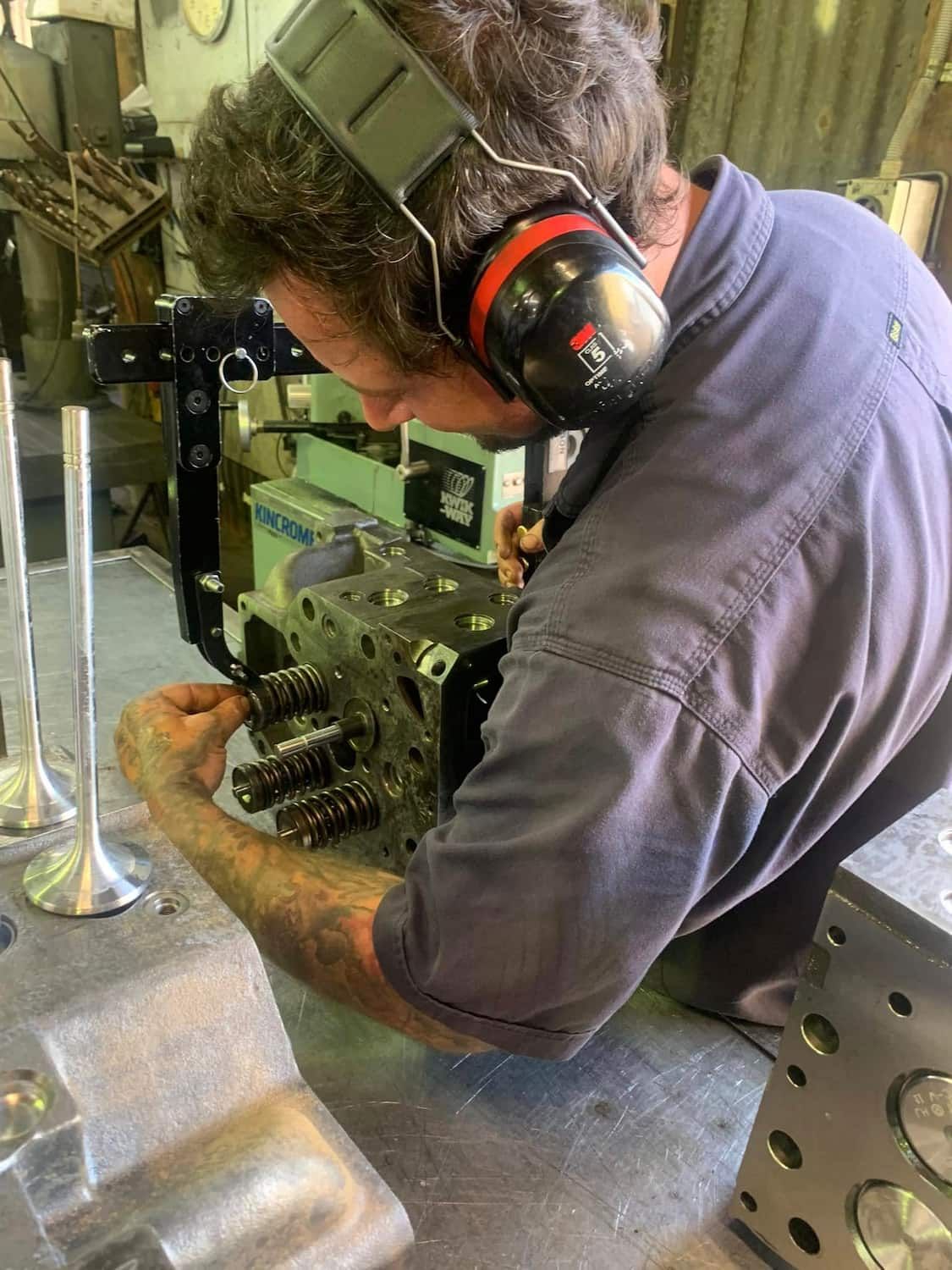A Man Wearing Headphones is Working on a Piece of Metal — Curtin Engine Reconditioning Pty Ltd In Paget, QLD