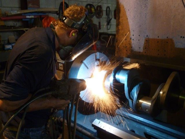a person is working on something metal with sparks flying— Curtin Engine Reconditioning Pty Ltd In Paget, QLD