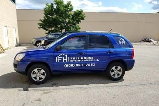 A blue SUV is parked in a parking lot in front of a building.