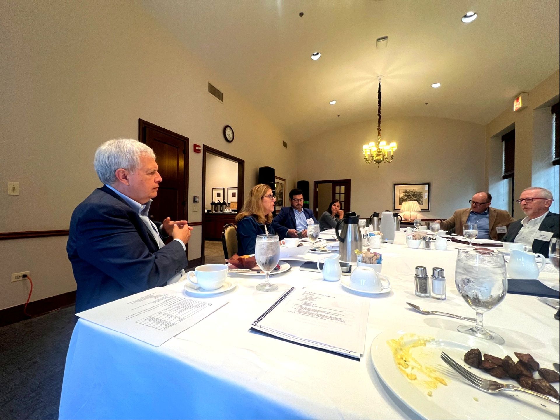 A group of people are sitting around a table shaking hands.