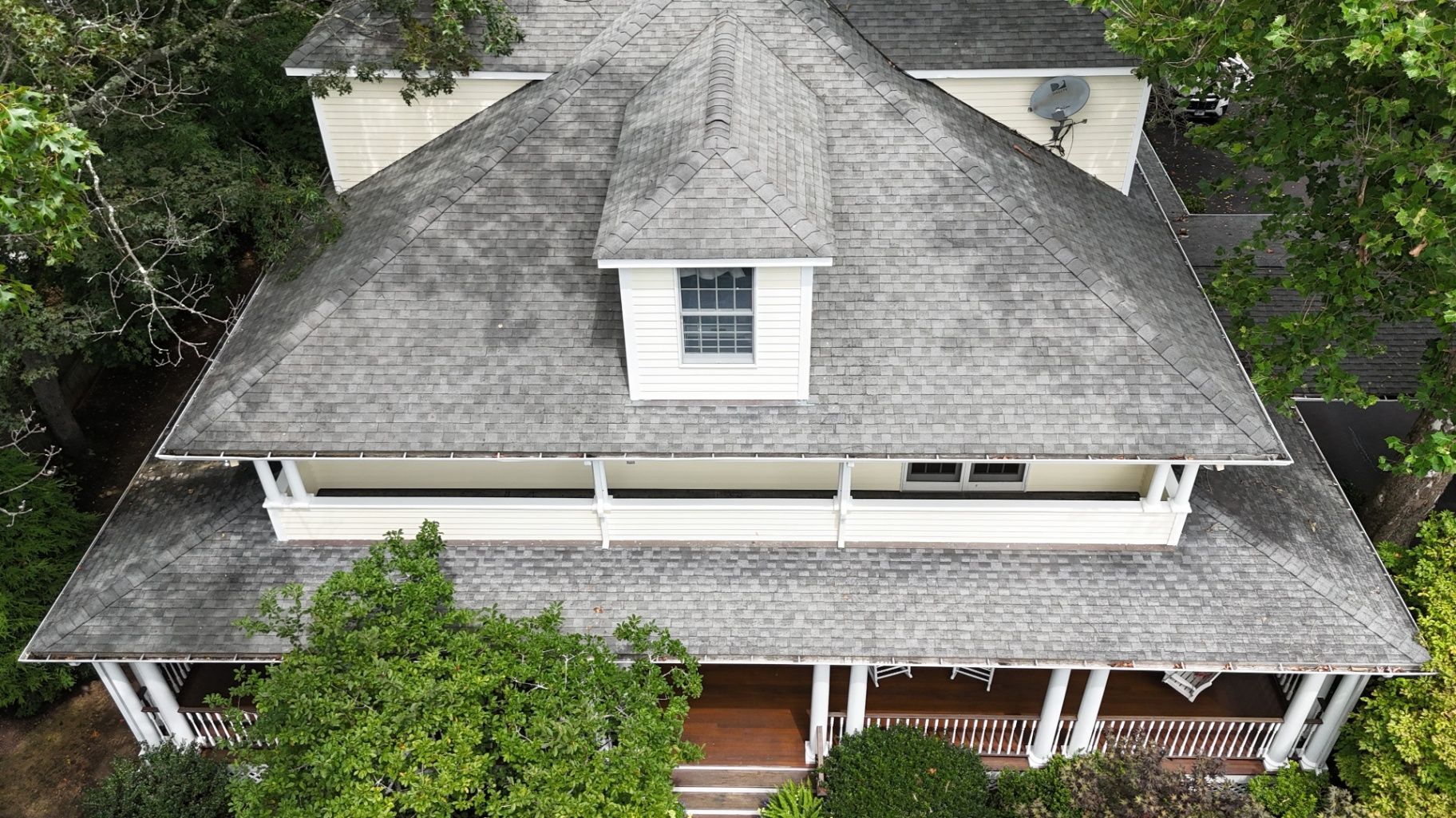 Overhead view of a house with a gray shingle roof, white trim, and a small dormer window.